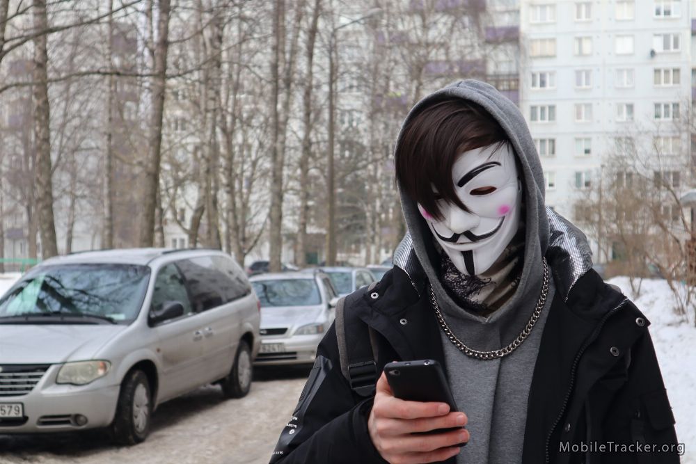 hacker anonymous mask holding phone